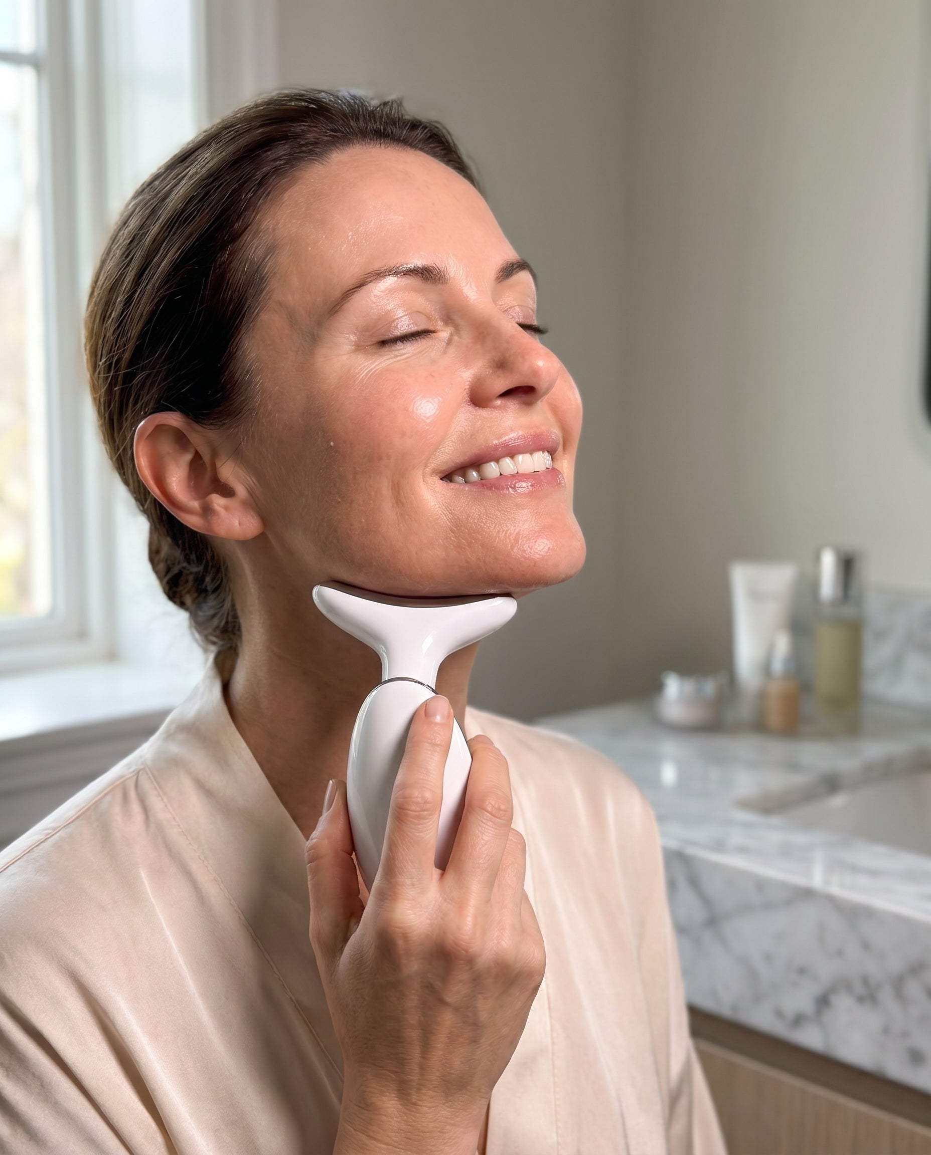 Woman using the Auré LED facial sculptor along her jawline